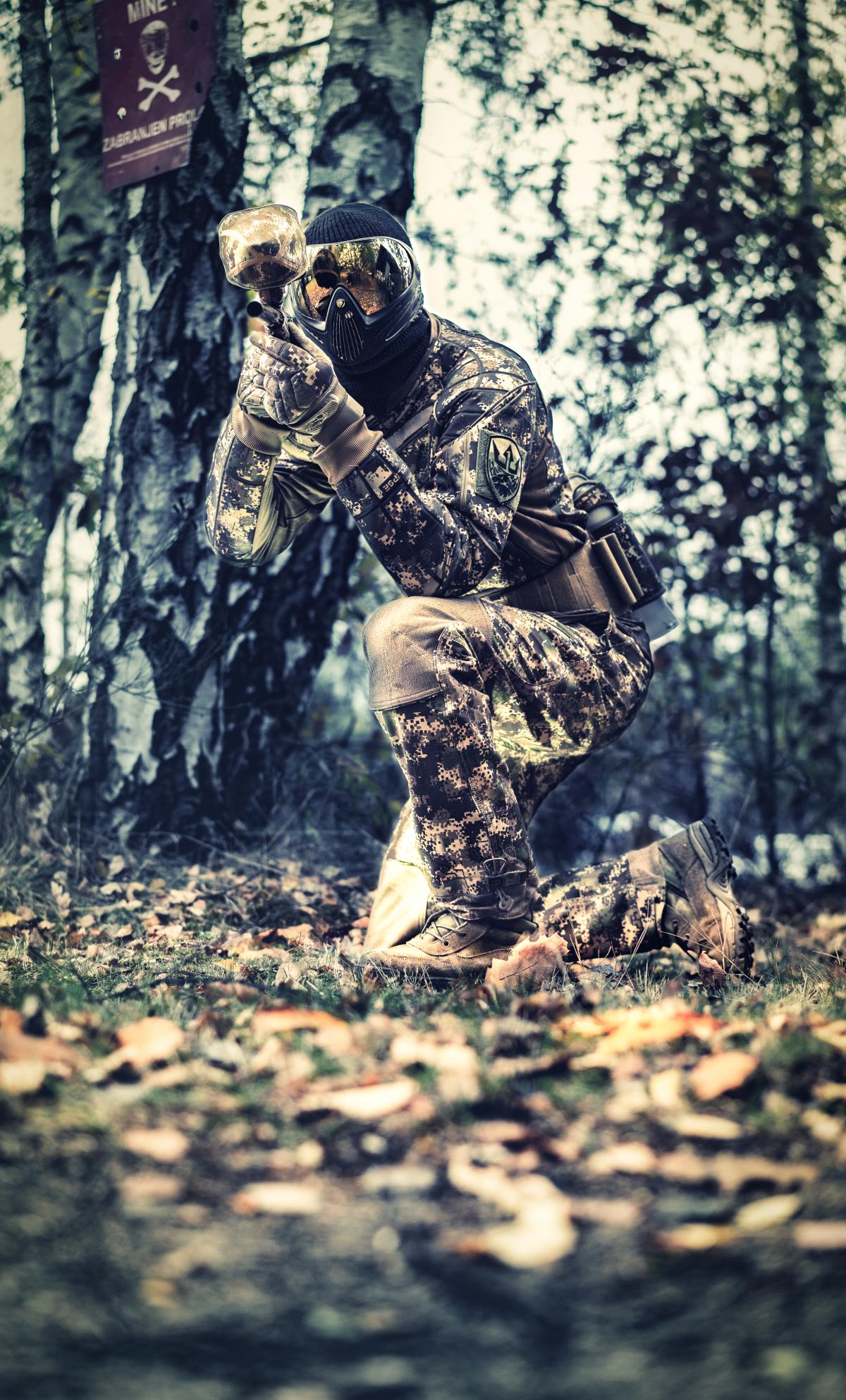 Ein Paintballspieler im Freigelände auf der Lauer im Wald